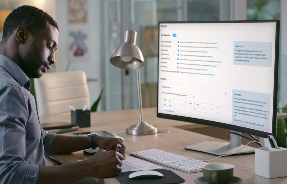 Man working at a computer, leveraging Dataiku built-in guardrails to enable scale while maintaining control